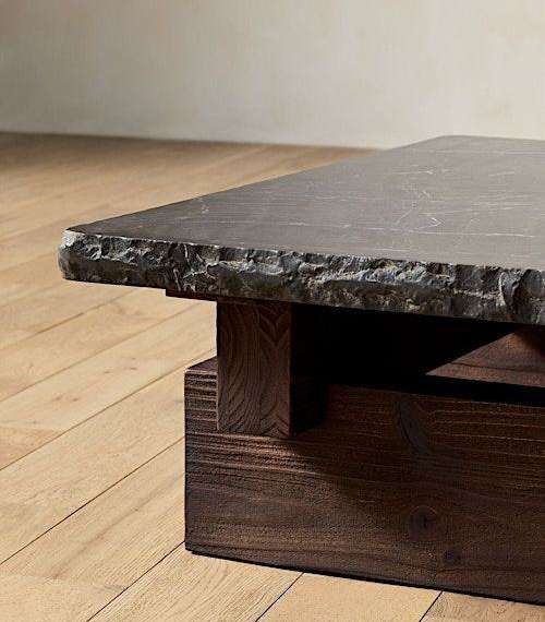 Rough-edged dark stone tabletop on a substantial timber base.